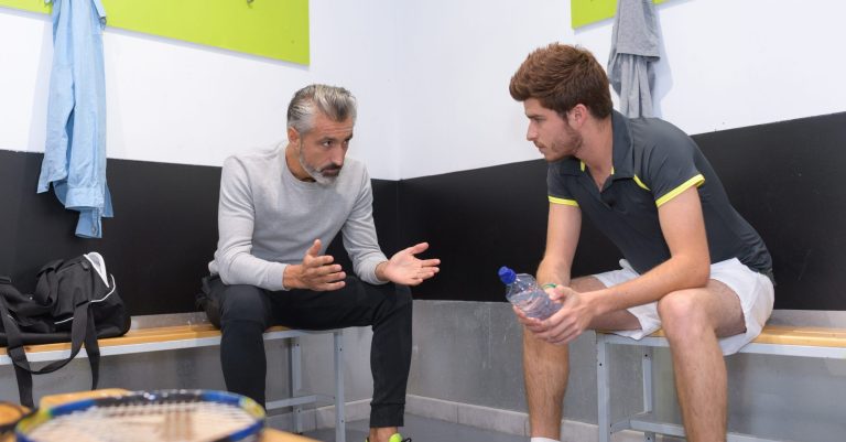 coach talking to tenis player in locker room